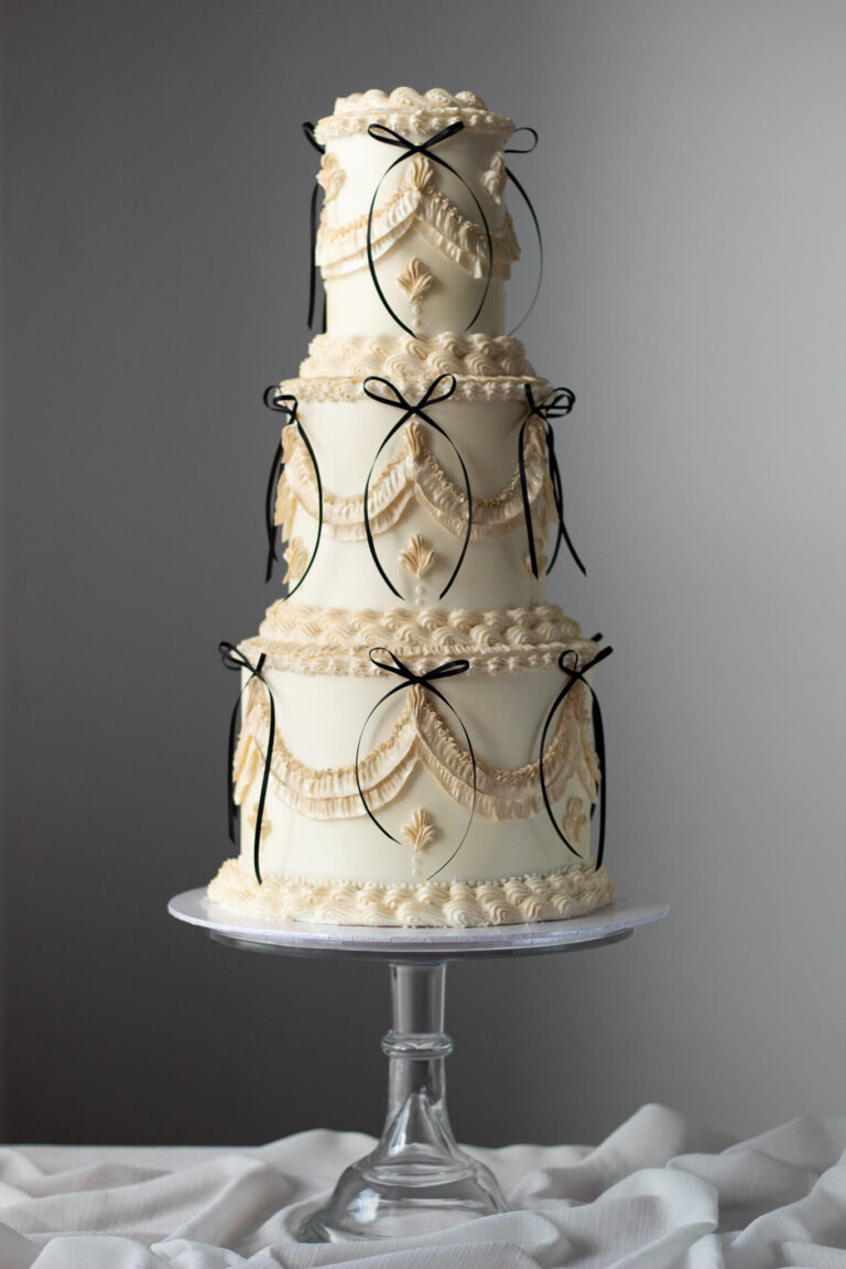3 tier ivory shimmer vintage wedding cake with black bow details