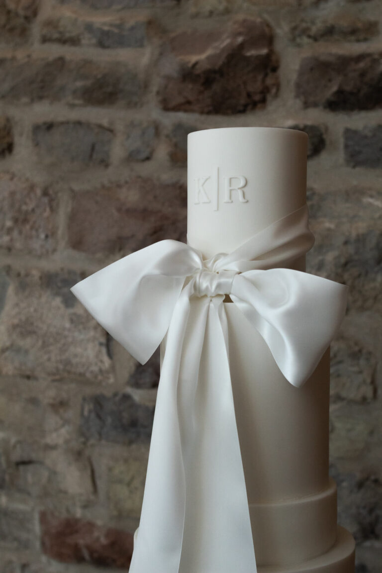 tall white satin bow and monogram wedding cake 9669