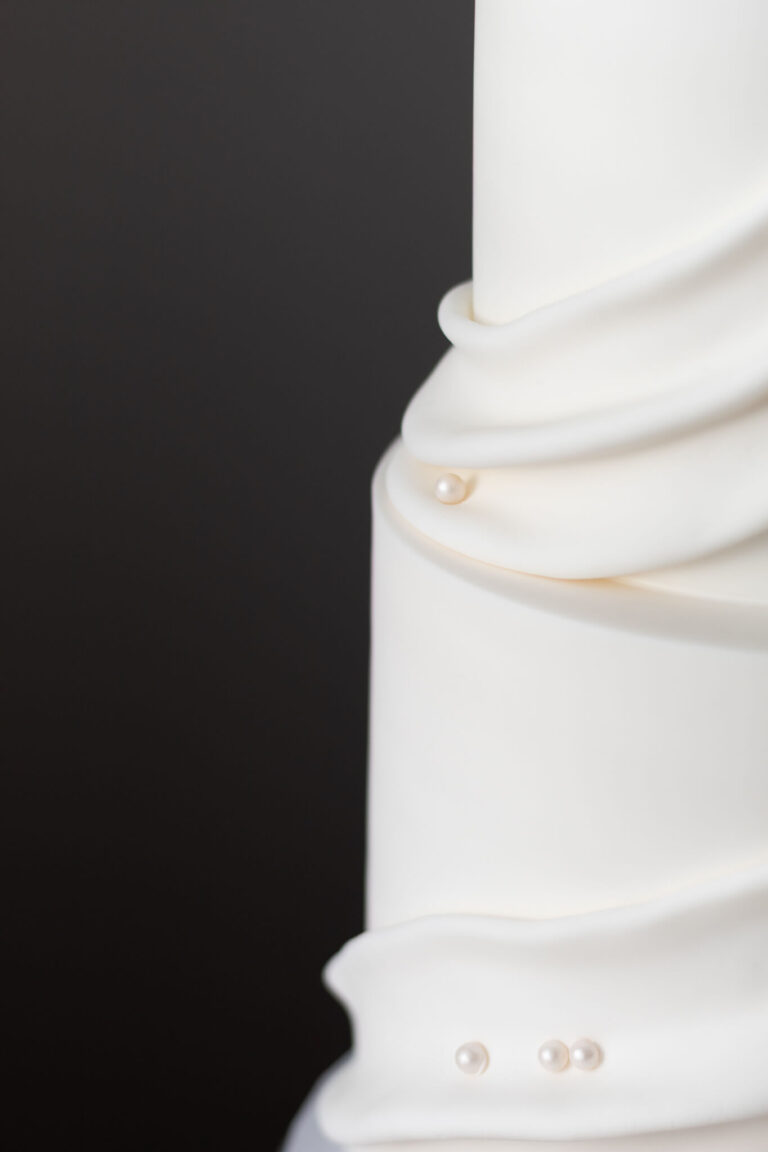 white fabric draped wedding cake with pearl details