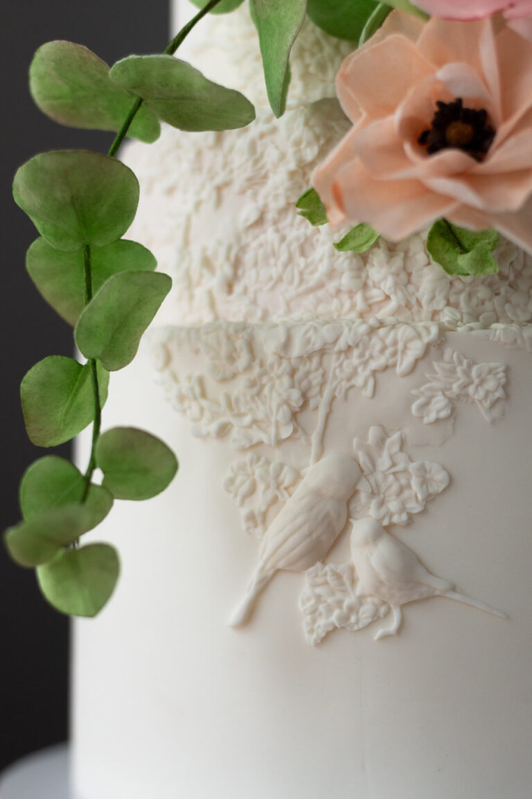 white wedding cake with floral bird bas relief detail and wafer paper flowers
